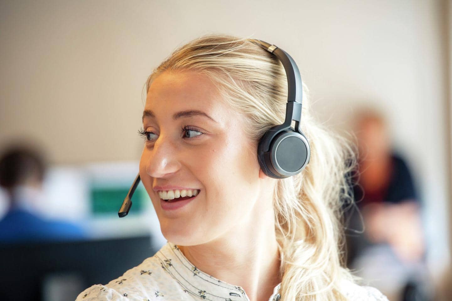 Kvinde med headset smiler og kigger til siden