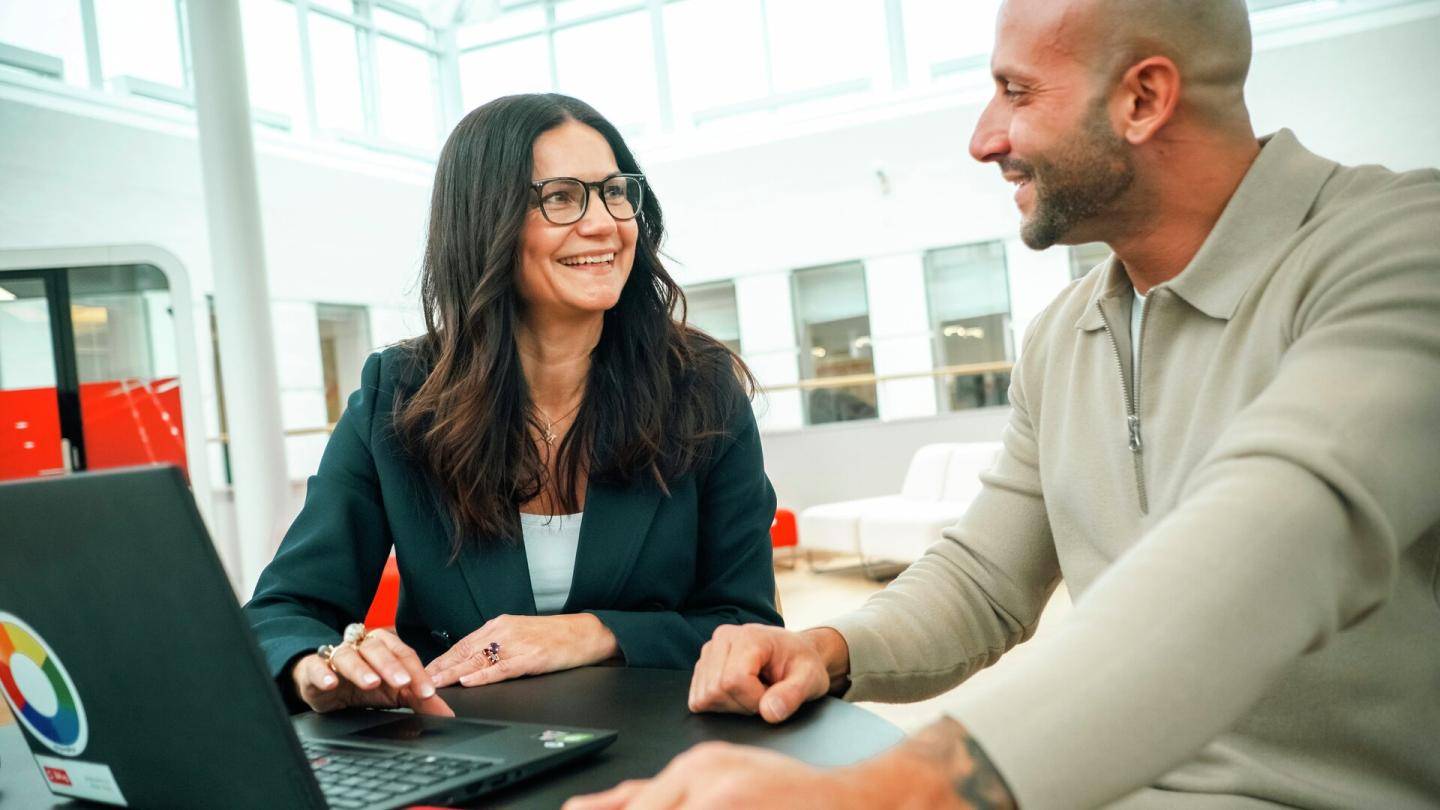 En kunde og en medarbejder sidder foran en computer