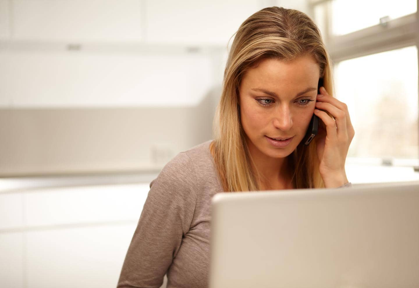 Kvinde der taler i telefon foran sin computer